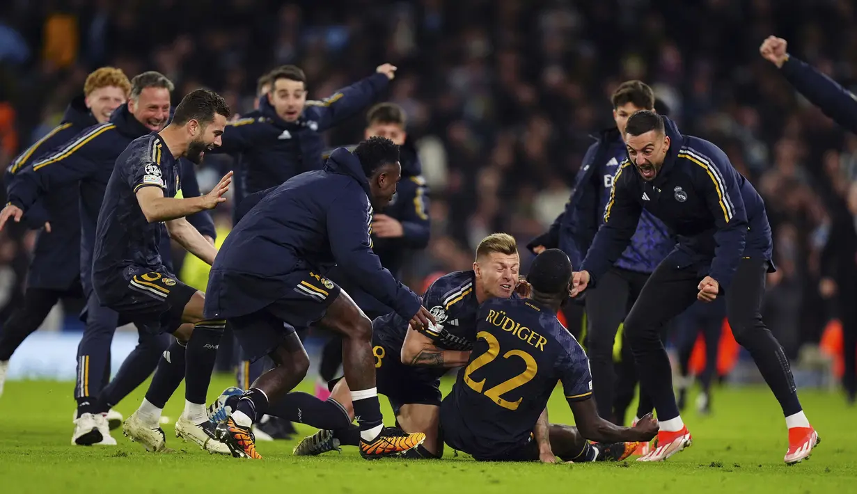 Para pemain Real Madrid merayakan gol penentu yang dicetak Antonio Rudiger ke gawang Manchester City saat adu tendangan penalti pada laga leg kedua perempatfinal Liga Champions 2023/2024 di Etihad Stadium, Manchester, Rabu (18/4/2024). Real Madrid menang 4-3 dalam adu penalti dan lolos ke semifinal. (PA via AP Photo/Mike Egerton)