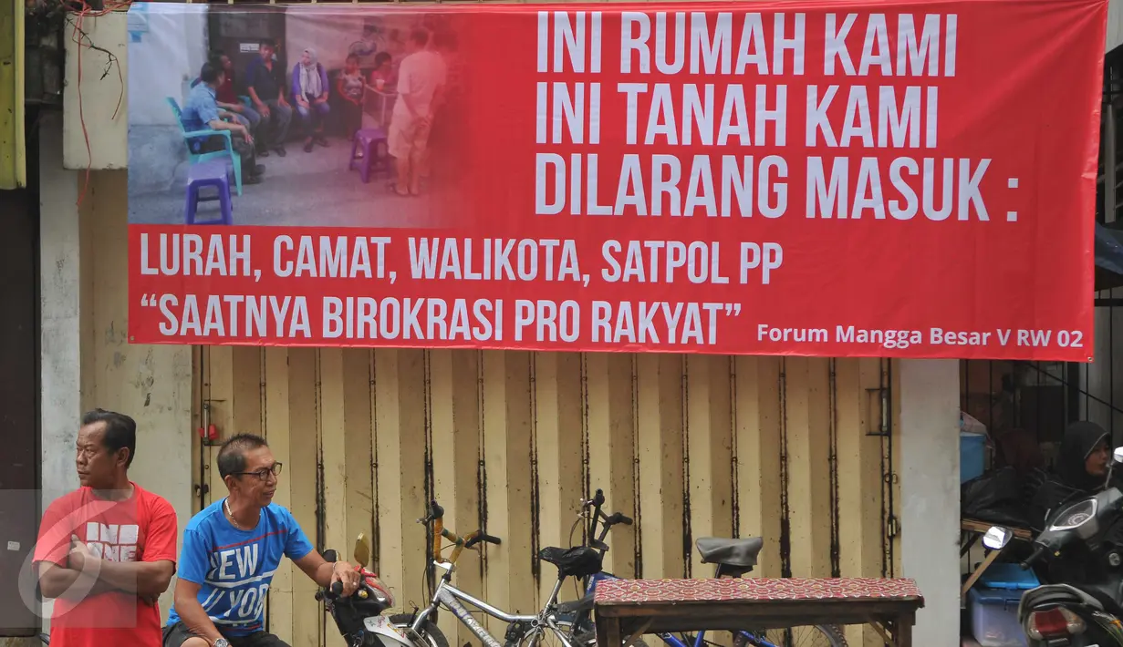 Warga bersantai di dekat spanduk penolakan yang terpasang di kawasan jalan Mangga Besar, Jakarta, Senin (22/8). Spanduk itu dipasang warga RW2 Kelurahan Mangga Besar sebagai aksi menolak penggusuran rumah mereka. (Liputan6.com/Gempur M Surya)