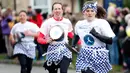 Para peserta mengambil bagian dalam lomba lari sembari membawa wajan berisi pancake di Olney, Buckinghamshire, Inggris, Selasa (25/2/2020). Para peserta kompetisi tahunan tersebut harus membolak-balikan pancake sambil tetap berlari. (AP/Alastair Grant)