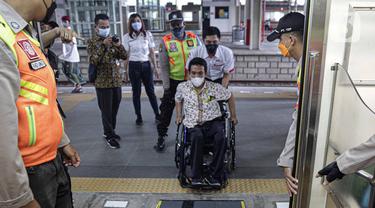 Petugas membantu penyandang disabilitas naik ke kereta saat menjajal fasilitas di Stasiun Jatinegara, Jakarta, Jumat (3/12/2021). KAI Commuter mengajak pengguna transportasi dengan disabilitas untuk merasakan sarana dan prasarana perkeretaapian yang lebih aksesibel. (Liputan6.com/Faizal Fanani)