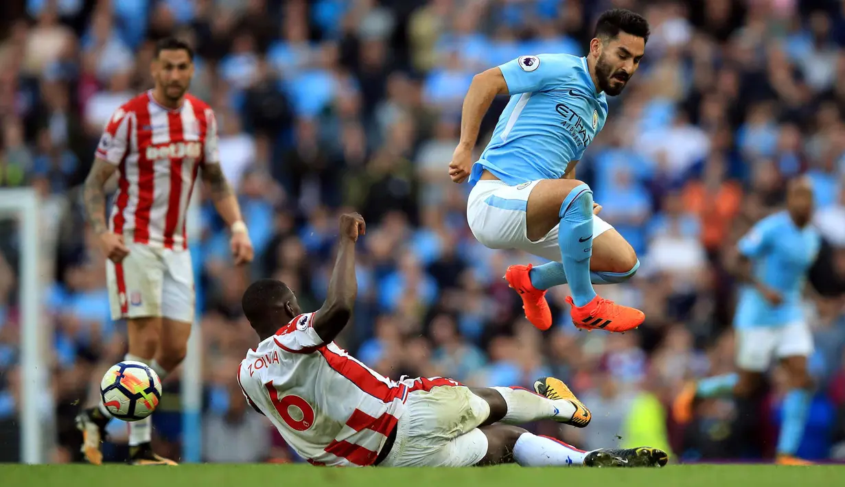 Bek Stoke City, Kurt Zouma berusaha merebut bola yang dibawa Gelandang Manchester City, Ilkay Gundogan saat bertanding pada lanjutan Liga Inggris di Etihad Stadium, Manchester, (14/10). City menang 7-2 atas Stoke. (Mike Egerton / PA via AP)