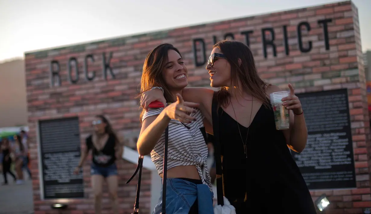 Dua penonton wanita tersenyum saat menghadiri Rock in Rio Festival di Olympic Park, Rio de Janeiro, Brazil, (22/9). Festival ini berlangsung  selama tujuh hari 15-17 September dan 21-24. (AFP Photo/Mauro Pimentel)