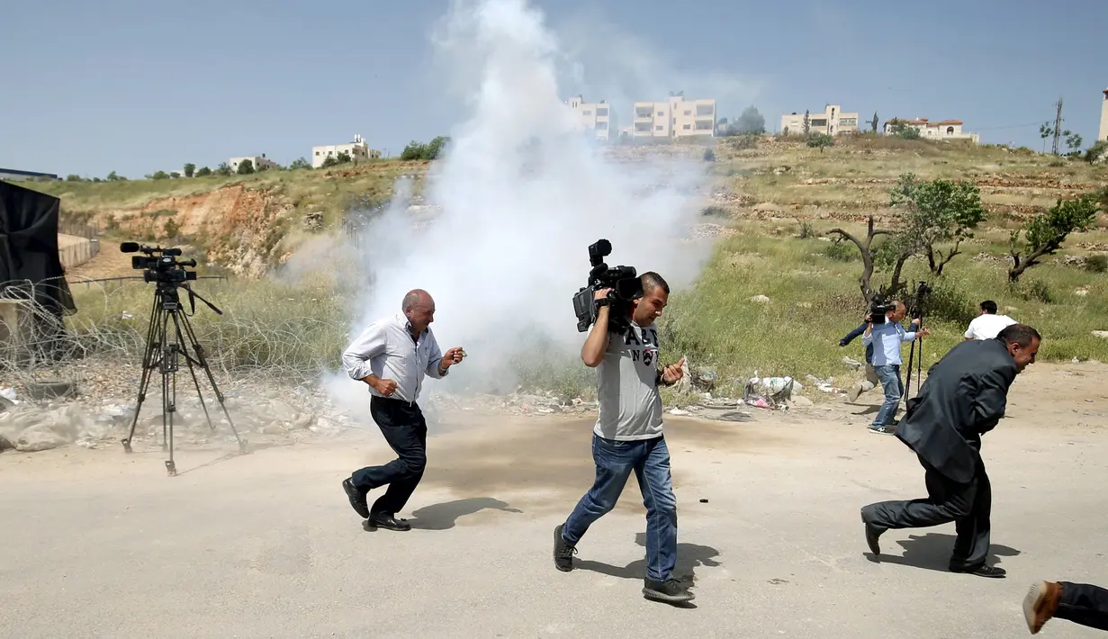 Wartawan Palestina berlari berhamburan setelah gas air mata ditembakkan pasukan Israel, Penjara Ofer Israel di Ramallah, Israel (26/4). Sejumlah wartawan menjadi sasaran tembakan gas air mata pasukan Israel. (REUTERS / Mohamad Torokman)