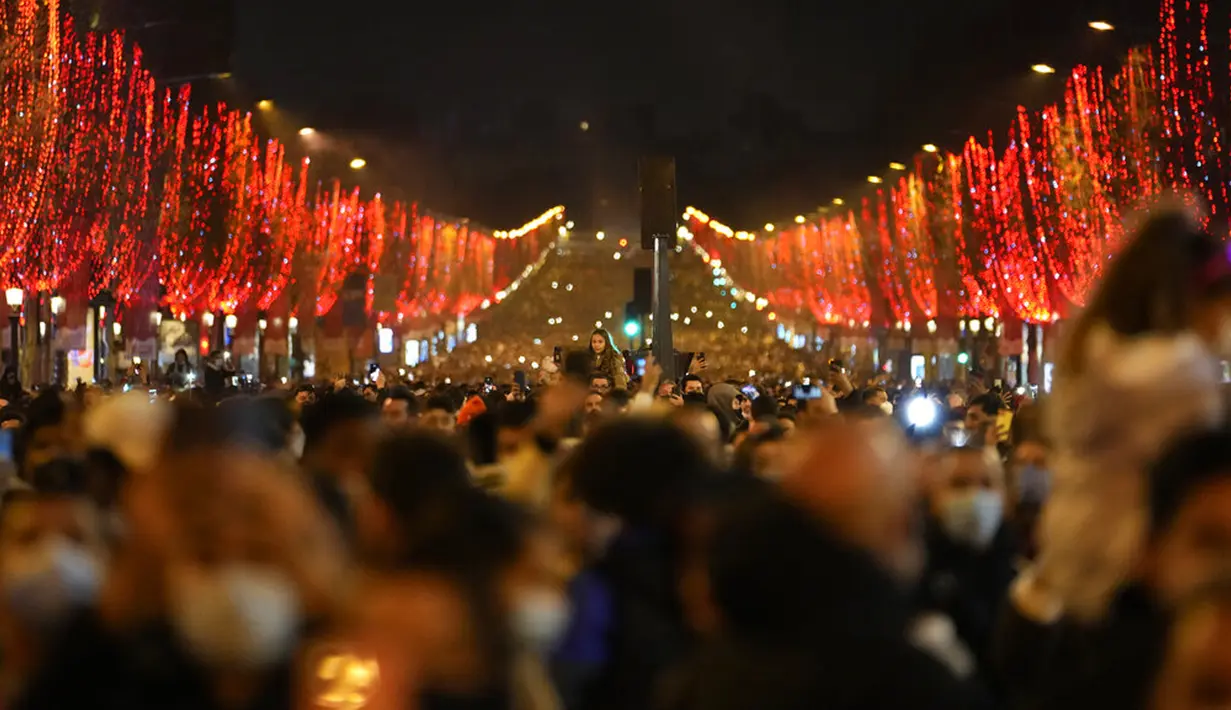 Orang-orang merayakan malam Tahun Baru di Jalan Champs Elysees, Paris, Prancis, Jumat (31/12/2021). (AP Photo/Thibault Camus)