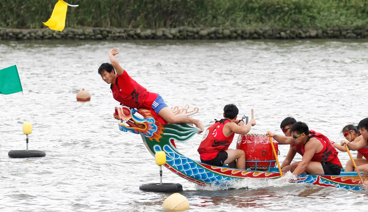 Seorang kapten berhasil meraih bendera usai mencapai garis finish perlombaan tradisional China, Dragon Boat di Taipei, Taiwan, Minggu (28/5). Perlombaan ini untuk mengenang kematian penyair Qu Yuan yang tenggelam pada 278 SM. (AP Photo/Chiang Ying-ying)