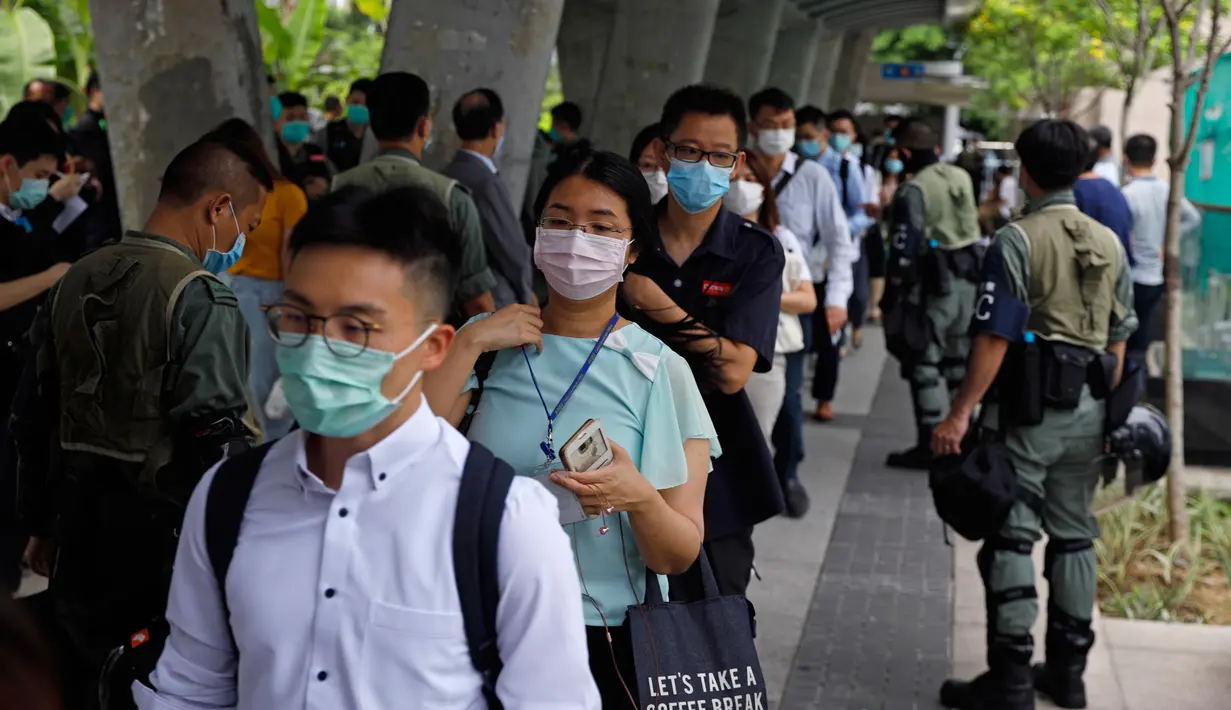 Polisi anti huru hara memeriksa kartu identitas pekerja di dekat Gedung Dewan Legislatif di Hong Kong, Rabu (27/5/2020). Penjagaan ekstra dilakukan menimbang kemungkinan aksi menentang RUU lagu nasional China dan rencana Beijing menerapkan UU keamanan nasional. (AP Photo/Kin Cheung)