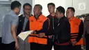 KPK juga menyita sejumlah barang bukti. Barang bukti tersebut di antaranya beberapa dokumen, Barang Bukti Elektronik (BBE), beberapa pasang sepatu, serta uang tunai sebesar Rp 335,4 juta. Tampak dalam foto, Bupati Tulungagung, Gatut Sunu Wibowo (ketiga kiri) dibawa petugas menuju mobil tahahan usai menjalani pemeriksaan intensif di Gedung Merah Putih Komisi Pemberantasan Korupsi (KPK), Jakarta, Minggu (12/4/2026) dini hari WIB. (Liputan6.com/Helmi Fitrhiansyah)
