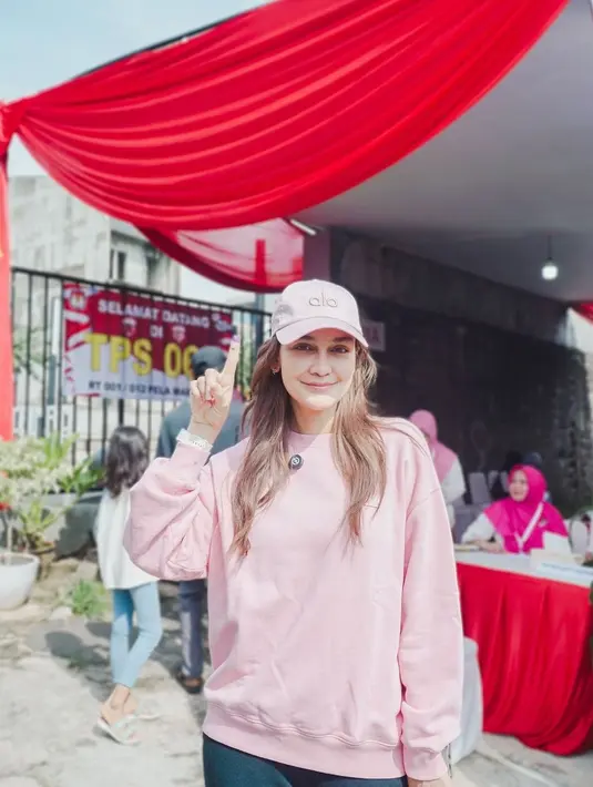 Luna Maya turut gunakan hak pilihnya dengan busana yang santai. Ia nampak kenakan sweater dan topi pink dari Alo dengan celana jeans [@lunamaya]