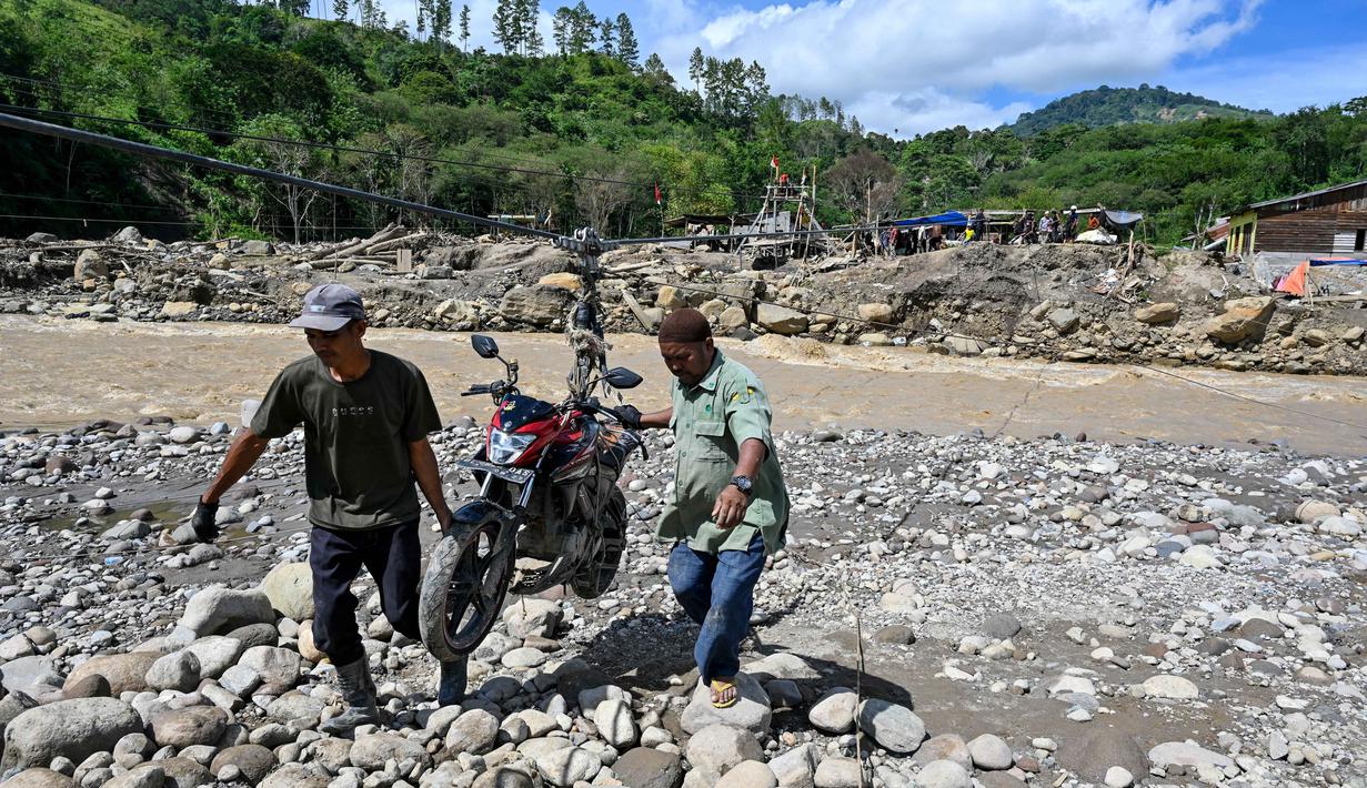 Keberadaan tali sling menjadi urat nadi bagi sejumlah desa di Kecamatan Ketol, Aceh Tengah, di antaranya Desa Kekuyang, Burlah, Bintang Pepara, dan Buge Ara. Tampak dalam foto, warga mengangkut sepeda motor menggunakan tali untuk menyeberangi sungai setelah banjir bandang yang menghancurkan desa-desa di sekitarnya di Ketol, provinsi Aceh, pada Selasa 6 Januari 2026. (CHAIDEER MAHYUDDIN/AFP)