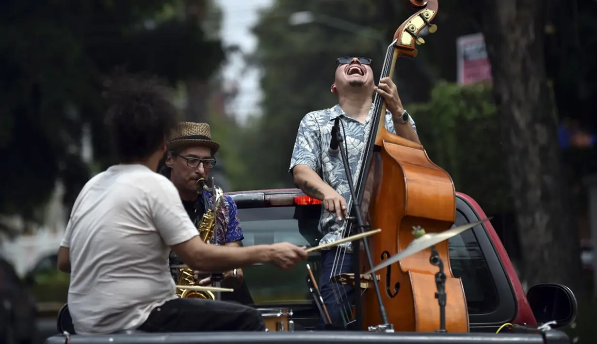 Band Maroto Jazz Trio yang terdiri dari Diego Maroto pada Saxophone, Jorge Molina pada double bass, dan Edy Vega pada drum tampil dari atas sebuah van melewati kawasan Mexico City, Meksiko, 29 Agustus 2020. Penampilan mereka dilakukan di tengah pandemi virus corona COVID-19. (RODRIGO ARANGUA/AFP)
