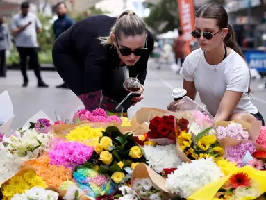Orang-orang meletakkan bunga di luar pusat perbelanjaan Westfield Bondi Junction di Sydney pada 14 April 2024. (DAVID GRAY/AFP)