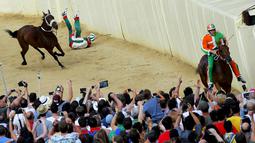 Seorang joki terjatuh saat beraksi dalam lomba pacuan kuda tahunan Palio di Siena, Italia. (Reuters/Fabio Muzzi)