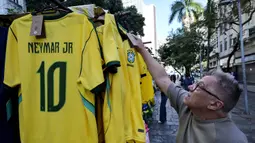 Seorang pria melihat kaus tim sepak bola nasional Brasil yang dipajang di pasar Saara, Rio de Janeiro, Brasil, pada Selasa 9 Juni 2026, menjelang turnamen Piala Dunia FIFA 2026. (Nelson ALMEIDA/AFP)