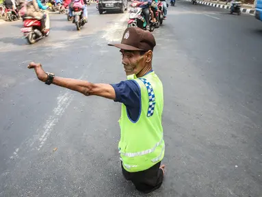 Pak Mamat (73 tahun) tengah mengatur arus lalu lintas di Jalan Raya Ciracas, Jakarta, Minggu (20/9/2015). Cacat fisik sejak lahir tidak membuat pria asli warga Ciracas ini putus harapan dalam menghidupi keluarganya. (Liputan6.com/Faizal Fanani)