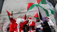 Pengunjuk rasa berkostum sinterklas (Santa Claus) memegang bendera Palestina dalam demonstrasi di Bethlehem, Tepi Barat, 23 Desember 2017. Mereka menentang kebijakan Presiden Donald Trump soal Yerusalem yang diklaim Ibu Kota Israel. (AP/Nasser Shiyoukhi)