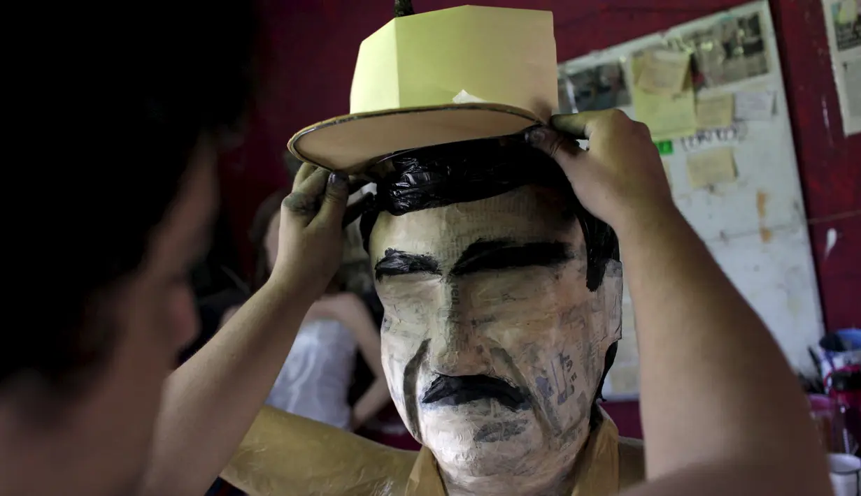 Pekerja memasangkan topi ke boneka raja narkoba Joaquin "El Chapo" Guzman saat menyelesaikannya di Reynosa, Meksiko (21/7/2015). Guzman melarikan diri dari penjara melalui terowongan yang ia buat pada bulan lalu. (REUTERS/Daniel Becerril)
