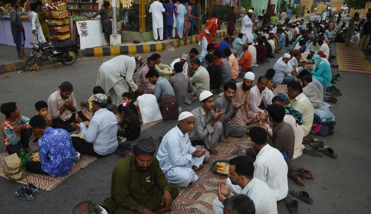 Muslim Pakistan berdoa sebelum berbuka puasa bersama di sepanjang jalan di Karachi pada 7 Mei 2019. Ketika bulan suci Ramadan mulai di Pakistan, banyak masyarakat muslim memanfaatkan buka puasa gratis yang disponsori oleh badan-badan amal dan orang-orang kaya. (RIZWAN TABASSUM / AFP)