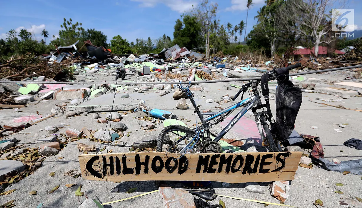 Sebuah papan dengan pesan Childhood Memories terpasang di sepeda di atas reruntuhan puing pasca gempa bumi dan tsunami di Jalan Trans Sulawesi, Palu, Sulawesi Tengah, Kamis (4/10). (Liputan6.com/Fery Pradolo)