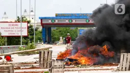 Warga membakar ban saat aksi menutup akses jalan menuju Gerbang Tol (GT) Jatikarya 1& 2, di Jalan tol Cimanggis-Cibitung, Bekasi, Jawa Barat, Rabu (8/2/2023). Dalam aksinya mereka menuntut Pengadilan Negeri Kota Bekasi segera menyelesaikan pembayaran atas penggunaan tanah untuk tol seluas 4,2 hektar. (Liputan6.com/Herman Zakharia)