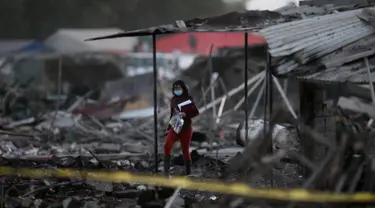 Seorang wanita berjalan di antara puing-puing bangunan rumah yang hancur dalam ledakan pasar kembang api terbesar di luar Ibu Kota Meksiko, Selasa (20/12). Sedikitnya 27 orang tewas dan lebih dari 70 lainnya terluka. (REUTERS/Edgard Garrido)