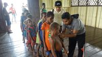 Satgas Kesehatan TNI memberi vaksin campak terhadap anak-anak di Kabupaten Asmat, Papua, Jumat (19/1). Tim Gabungan Satgas Kesehatan TNI KLB menyalurkan bantuan berupa vaksin ke kampung-kampung terpencil di Kabupaten Asmat. (LIputan6.com/Pool/Puspen TNI)
