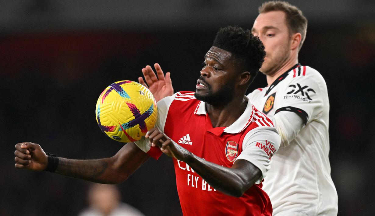 Gelandang Arsenal, Thomas Partey mneguasai bola dibayangi gelandang Manchester United, Christian Eriksen pada laga Liga Inggris 2022/2023 di Emirates Stadium, London (22/1/2023). Thomas Partey yang berkebangsaan Ghana didatangkan Arsenal dari Atletico Madrid pada awal musim 2020/2021 dengan mahar senilai 50 juta euro atau kini setara Rp818 miliar. (AFP/Glyn Kirk)