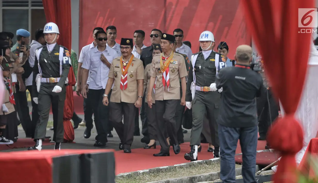 Presiden Joko Widodo didamping Ketua Kwarnas Pramuka Adhyaksa Dault tiba menghadiri perayaan hari jadi Pramuka yang ke-57 di Lapangan Gajah Mada, Wiladatika, Cibubur, Jakarta, Selasa (14/8). (Liputan6.com/Faizal Fanani)