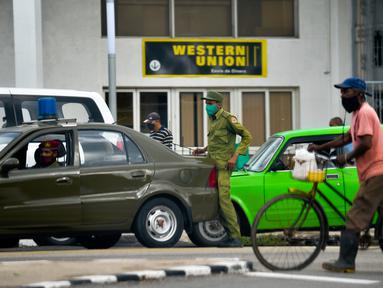 Petugas keamanan terlihat di luar Western Union sebelum penutup kantor di Havana, Kuba, Senin (23/11/2020). Layanan transfer uang terkemuka di dunia itu menutup lebih dari 400 gerainya di Kuba menyusul sanksi ekonomi terbaru yang dikeluarkan Amerika Serikat (AS) terhadap negara itu. (Yamil LAGE/AFP)