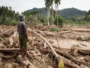 Seorang pria melihat kerusakan yang disebabkan oleh banjir yang membawa sisa-sisa pembalakan liar di Pelangai Gadang, Sumatera Barat, pada Sabtu 15 Maret 2025. (REZAN SOLEH/AFP)