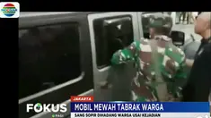 Sejumlah warga berusaha menghentikan sebuah mobil mewah bernomor polisi B 123 DAA yang baru saja menabrak seorang panitia lomba lari maraton.