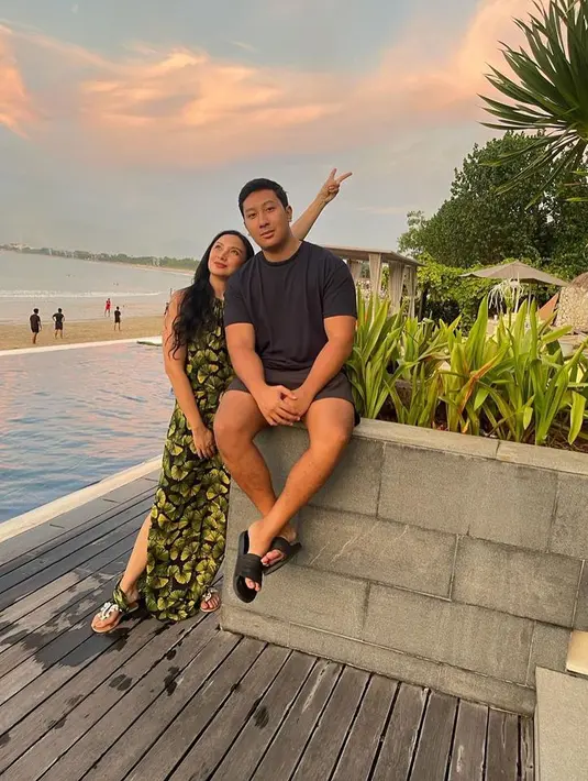 Di sini Tata Cahyani tampil awet muda berpose di samping Darma Mangkuluhur. Tata mengenakan sebuah dress panjang tanpa lengan bercorak floral. [Foto: Instagram/tatacahyani]