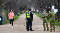 Petugas kepolisian dan tentara berpatroli di jalur lari yang populer di Melbourne, Selasa (4/8/2020). Melbourne memasuki pembatasan Tahap 4 dengan aturan yang lebih ketat sebagai upaya untuk membatasi pergerakan masyarakat dan penyebaran COVID-19. (William WEST / AFP)