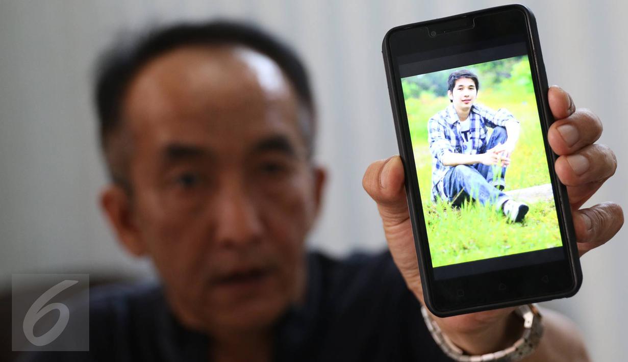 Keluarga yang menunggu di RS Polri menunjukkan foto Christopher, korban terbakarnya KM Zahro Express, Kramat Jati, Jakarta, Senin (2/1). (Liputan6.com/Immanuel Antonius)