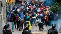 Para pengunjuk rasa dan polisi anti huru hara bentrok di Bogota, Kolombia, pada Jumat 22 November 2019. (AFP)