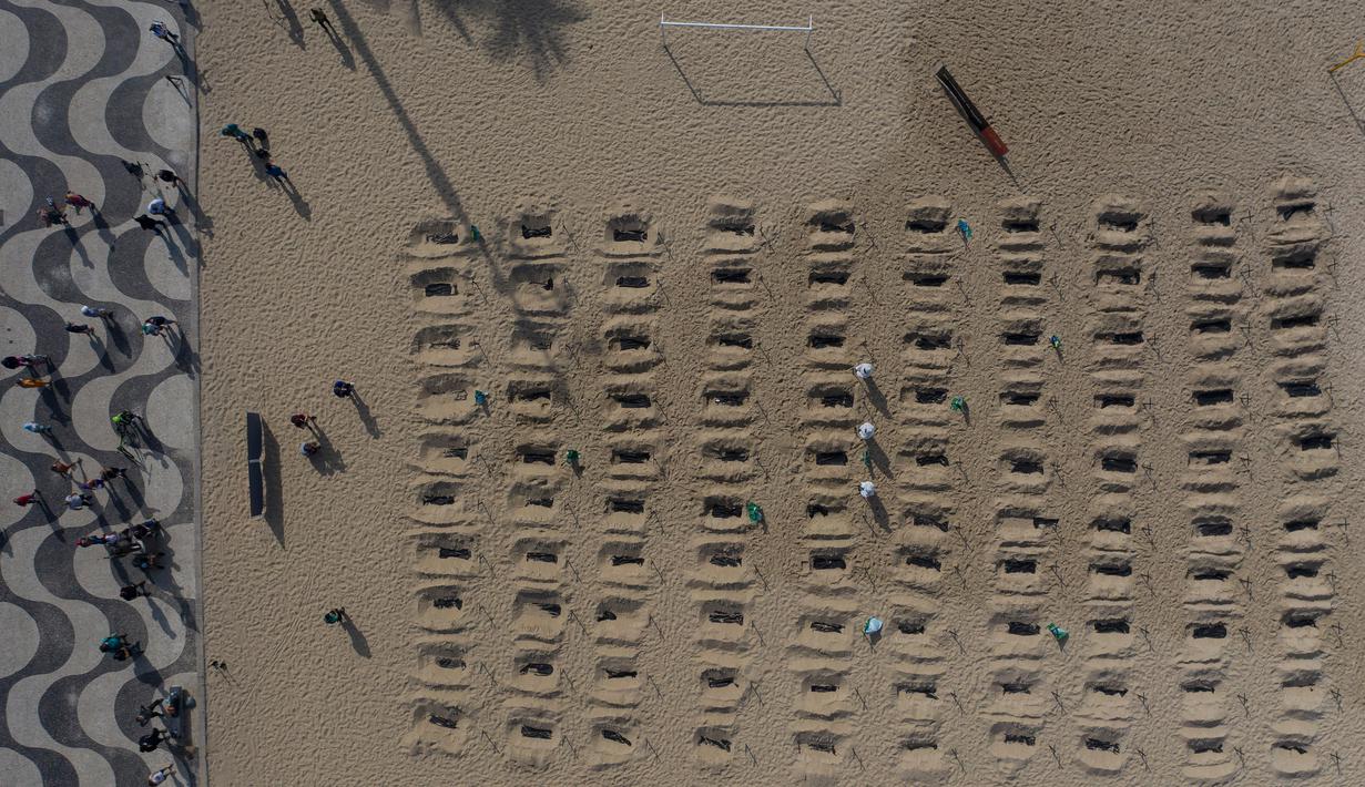 Aktivis menggali kuburan di pantai Copacabana, Rio de Janeiro, Kamis (11/6/2020). Aksi simbolis yang dilakukan oleh kelompok LSM Rio de Paz itu sebagai bentuk protes atas respons pemerintah Brasil dalam menangani pandemi Covid-19. (AP Photo/Leo Correa)