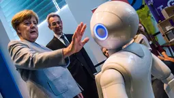 Kanselir Jerman Angela Merkel berinteraksi dengan robot interaktif di pameran Girl's Day di Berlin, Rabu (26/4). Pameran ini bertujuan menarik wanita muda untuk menggeluti pekerjaan hi-tech dan engineering. (AFP PHOTO / John MACDOUGALL)