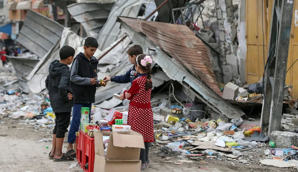 <p>Anak-anak Palestina berjualan manisan pada hari kelima gencatan senjata sementara antara Hamas dan Israel di depan reruntuhan bangunan kamp pengungsi Jebaliya, Jalur Gaza, 28 November 2023. (AP Photo/Mohammed Hajjar)</p>