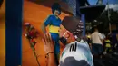 Seorang fans mencium poster Diego Maradona di Buenos Aires, Argentina, Rabu (25/11/2020). legenda sepak bola Argentina itu meninggal dunia pada usia 60 tahun setelah menderita serangan jantung. (AP/Natacha Pisarenko)