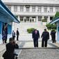 Presiden Amerika Serikat, Donald Trump bersama Pemimpin Korea Utara, Kim Jong-un berjalan menuju garis yang memisahkan kedua wilayah Korea di zona demiliterisasi Korea (DMZ), Desa Panmunjom pada Minggu (30/6/2019).  (Brendan Smialowski/AFP)