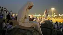 Seorang jemaah Muslim menggunakan telepon seluler untuk membaca ayat-ayat dari Al-Quran di atas bukit berbatu yang dikenal sebagai Jabal Rahmah atau Gunung Rahmat, di Dataran Arafah, selama ibadah haji tahunan di dekat kota suci Mekah, Arab Saudi, Selasa 26 Mei 2026. (AP Photo/Altaf Qadri)