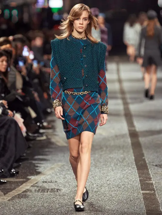 Gaun jumper Argyle dengan motif tartan Skotlandia dan Inggris, memperlihatkan kemampuan Virginie Viard dalam  bermain dengan dinamika maskulin-feminin - kode Chanel yang klasik. Dihiasi dengan permata yang indah dan mengesankan karya Goossens, memberikan kesan menggoda dan nakal.  [Dok/Chanel]