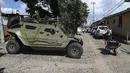 Seorang perempuan berjalan di depan mobil lapis baja tentara saat tentara berpatroli di jalan-jalan di Comasagua, El Salvador, Senin (3/10/2022). Geng-geng El Salvador, yang diperkirakan berjumlah sekitar 70.000 anggota, telah lama menguasai petak-petak wilayah dan memeras dan membunuh tanpa hukuman. (AP Photo/Salvador Melendez)