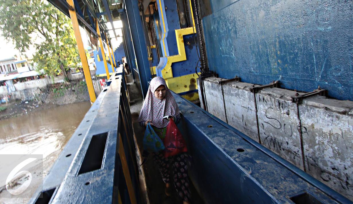 Warga melintasi jalan setapak di pintu air Petamburan, Jakarta, Jumat (17/2). Warga terpaksa melewati pintu air karena tidak ada jembatan penyeberangan orang di kawasan tersebut. (Liputan6.com/Immanuel Antonius)