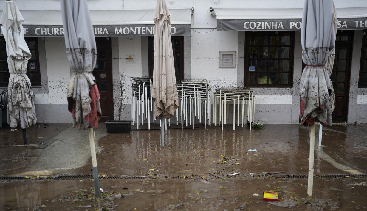 Payung memiliki tanda ketinggian yang dicapai air di luar sebuah restoran yang banjir semalaman di Alges, tepat di luar Lisbon, Selasa (13/12/2022). Badai Atlantik menghantam semenanjung Iberia, meninggalkan jejak kehancuran pada Selasa, terutama di Ibu kota Portugal,  Lisbon, sebelum pindah ke timur ke Spanyol.  (AP Photo/Armando Franca)