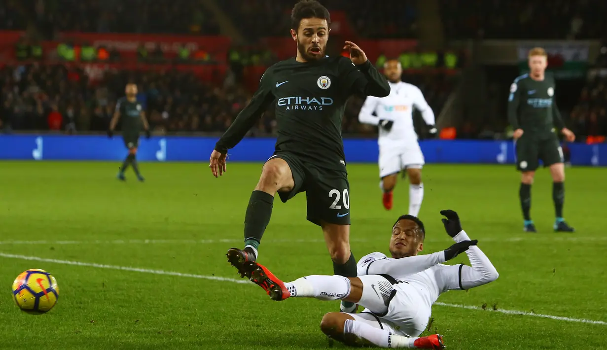 Gelandang Manchester City, Bernardo Silva berebut bola dengan pemain Swansea City, Jordan Ayew pada lanjutan Premier League di Liberty Stadium, Rabu (13/12). Bertandang ke Swansea City, Manchester City menang telak 4-0. (GEOFF CADDICK / AFP)