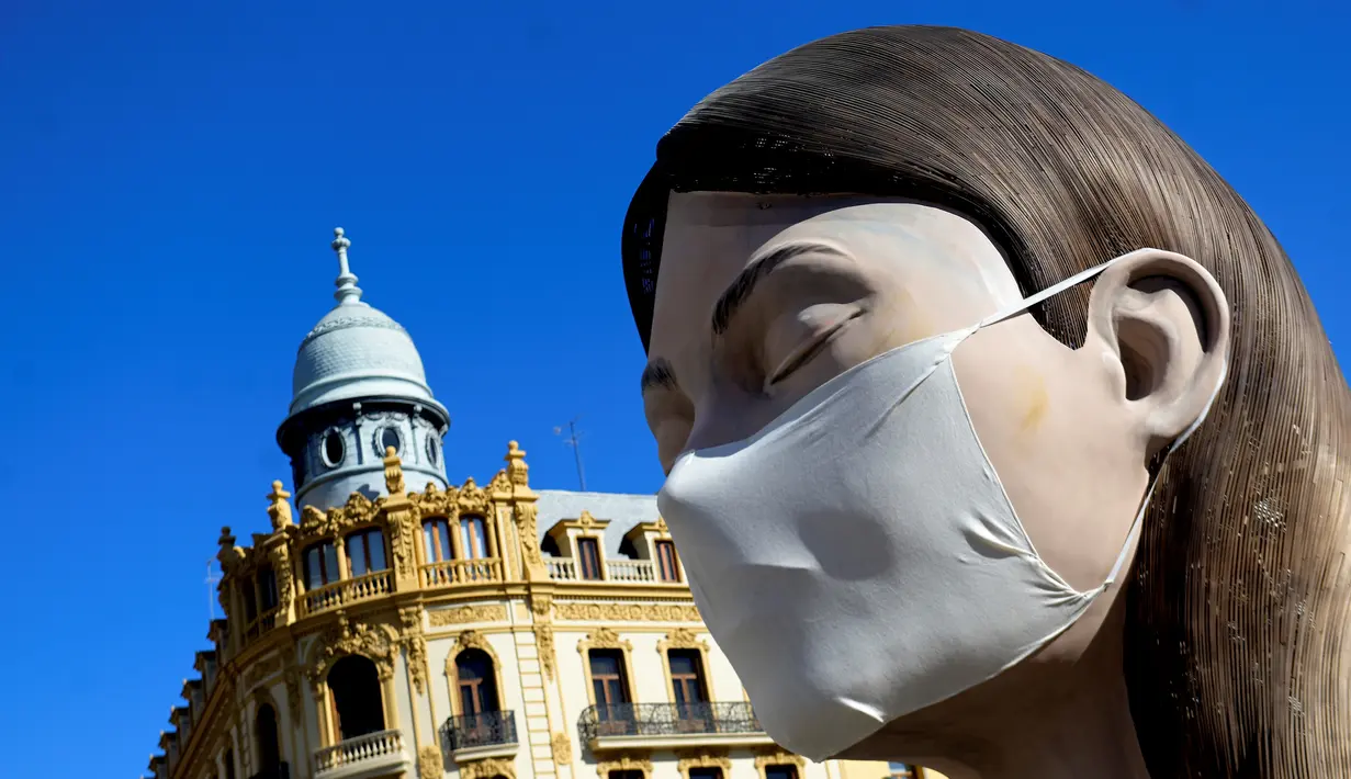 Patung raksasa yang akan ditampilkan di festival Las Fallas atau festival api terlihat mengenakan masker di Valencia, Spanyol, Rabu (11/3/2020). Festival Fallas yang akan berlangsung pada 13 Maret telah dibatalkan karena wabah coronavirus. (AFP/Jose Jordan)