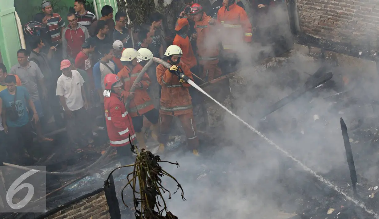 Petugas menyemprotkan air ke puing-puing yang terbakar untuk memastikan api benar-benar padam, Palmerah, Jakarta, Kamis (4/8). Api yang diduga berasal dari arus pendek itu membakar 8 rumah. (Liputan6.com/Immanuel Antonius)