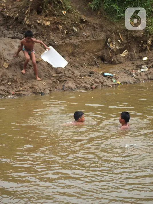 Sejumlah anak berenang di aliran Kali Ciliwung, Kampung Pulo, Jakarta, Jumat (2/12/2022).Minimnya lahan bermain menyebabkan anak-anak tersebut bermain tidak pada tempatnya, meskipun dapat membahayakan keselamatan. (merdeka.com/Imam Buhori)