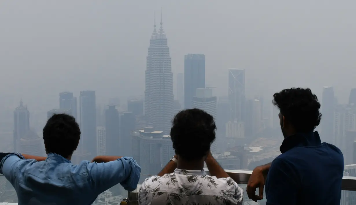 Wisatawan melihat cakrawala Kuala Lumpur, termasuk Menara Kembar Petronas, yang diselimuti kabut asap di Kuala Lumpur (11/9/2019). Kualitas udara turun ke tingkat "tidak sehat" di  sekitar Kuala Lumpur, menurut indeks polusi udara pemerintah. (AFP Photo/Mohd Rasfan)