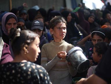 Anak-anak pengungsi Palestina berkumpul untuk menerima bagian makanan dari dapur amal di kamp pengungsi Nuseirat, yang terletak di bagian tengah Jalur Gaza, pada 21 Oktober 2025, atau sepekan setelah kesepakatan gencatan senjata antara Israel dan Hamas mulai berlaku. (Eyad BABA/AFP)